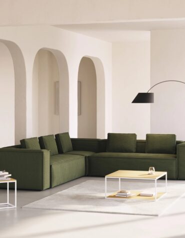 dunkelgrünes Polster Ecksofa in Wohnzimmer mit Stehlampe und Couchtisch auf weissem Teppich